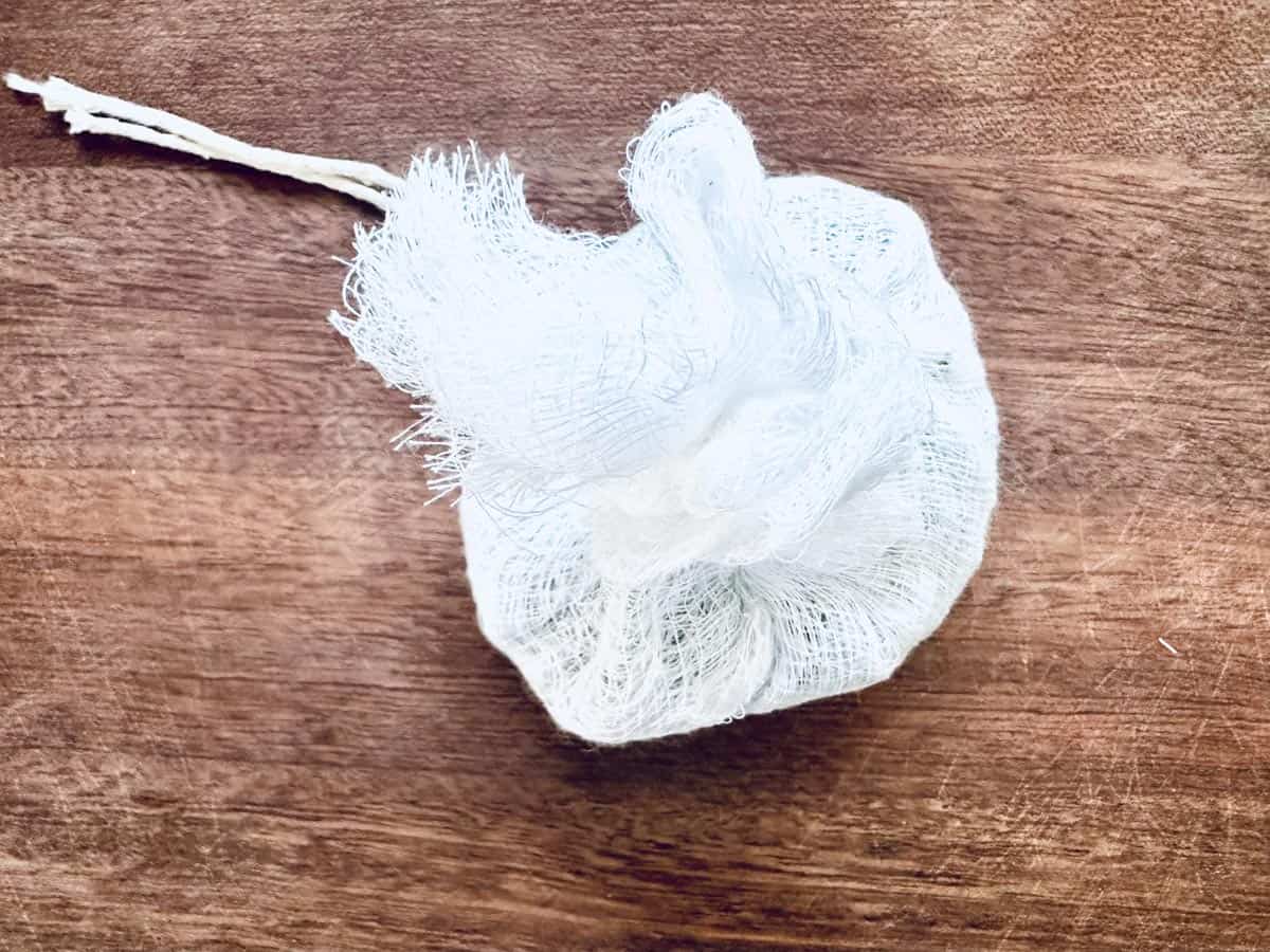 A small bundle of white cheesecloth tied with string rests on a wooden surface.