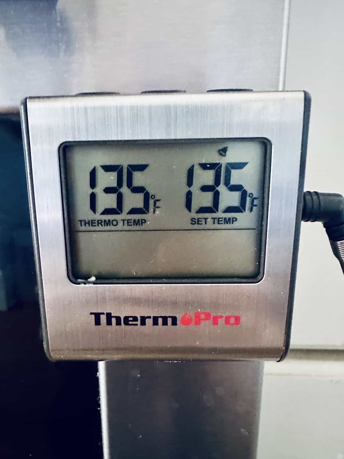 A ThermoPro digital thermometer displays a current temperature of 135°F and a set temperature of 135°F—ideal for perfectly cooked Oven-Baked Salmon with Lemon and Fresh Herbs. The silver device features a digital screen and connected probe.